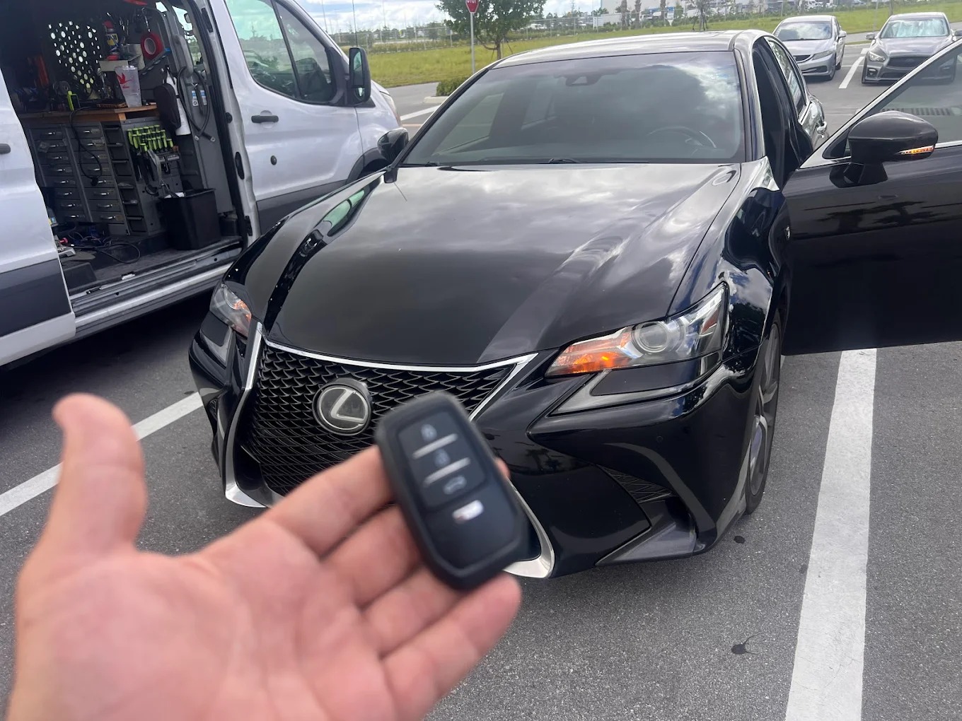 Automotive locksmith using BMW-compatible diagnostic tool to program new key fob connected to vehicle OBD-II port